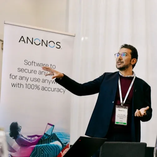 An Anonos team member speaking at an industry event with the Anonos banner behind.