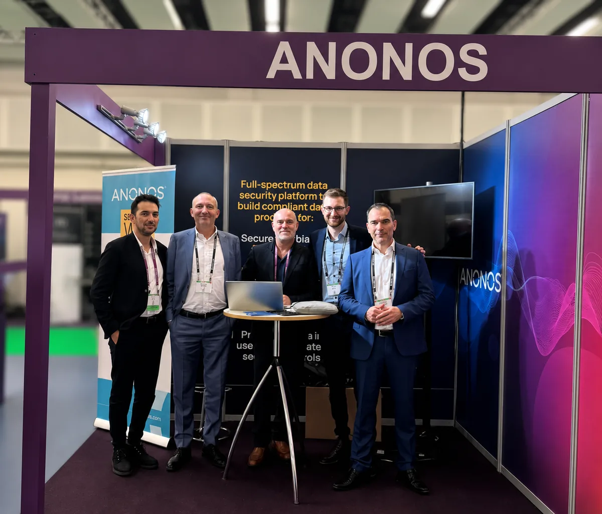 Anonos team members at a conference booth under the Anonos brand arch.